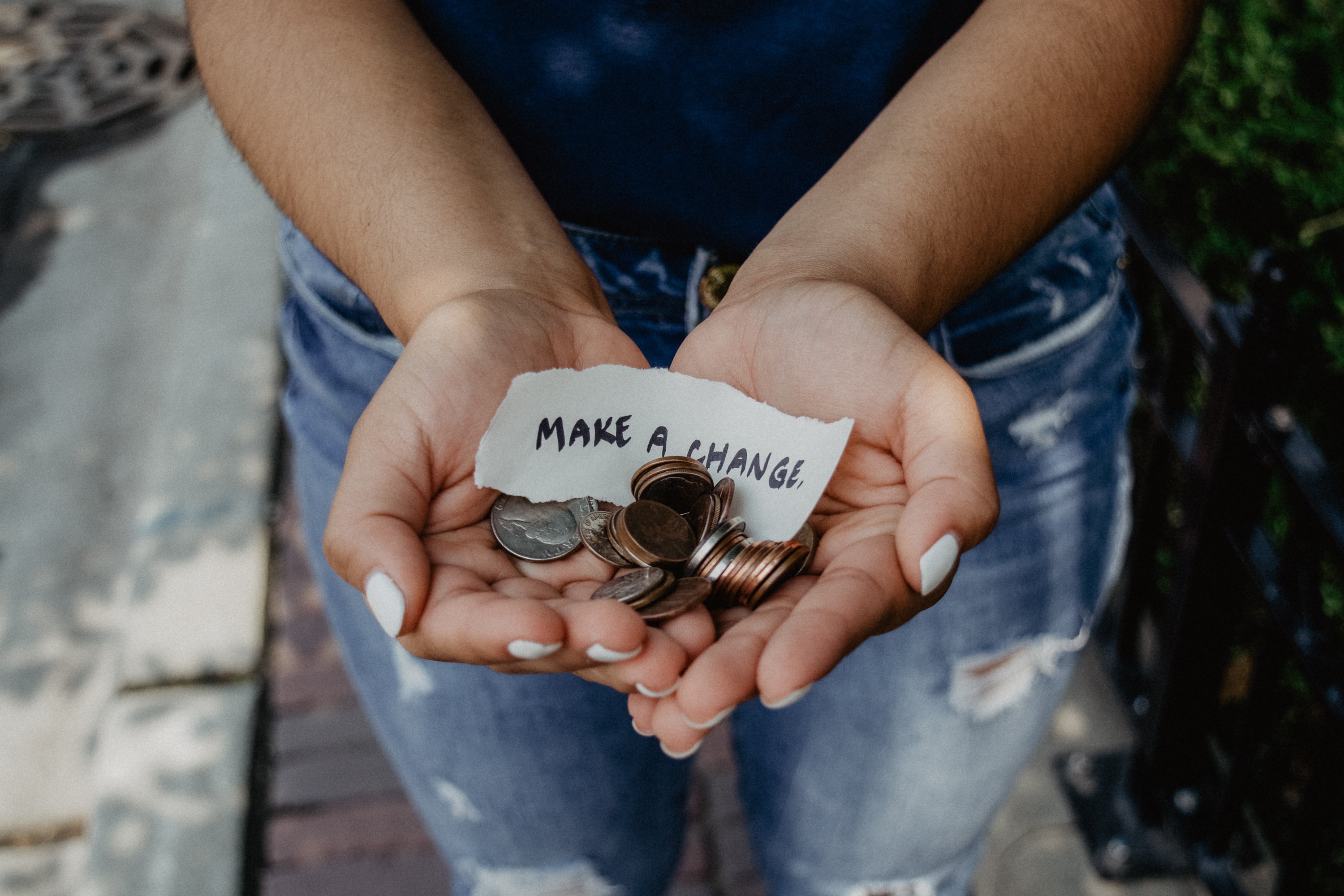 Female holding coins and a piece of paper with 'Make a change' written on it